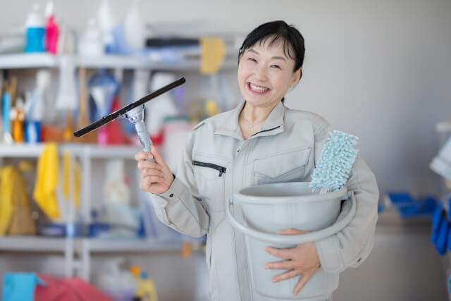 清掃道具を持つ笑顔の女性作業員