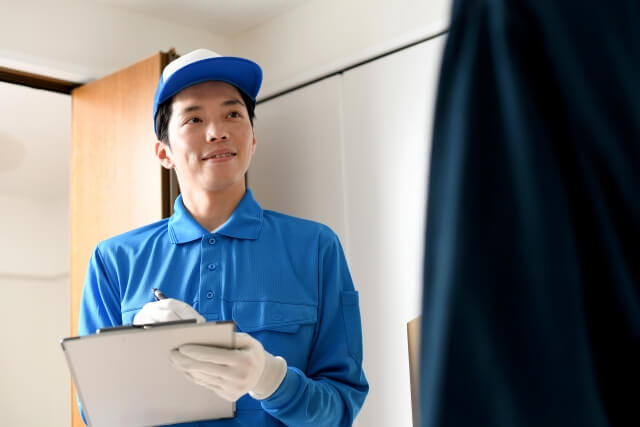 配達先で笑顔の青い制服の配達員