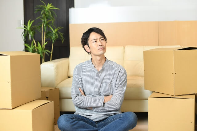 引っ越しを考える男性と段ボール
