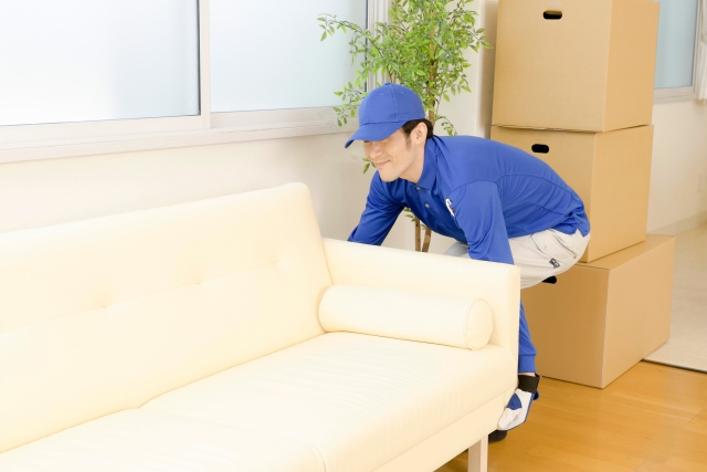 ソファを移動する青い作業着の作業員