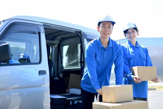 配送用バンから荷物を降ろす作業員